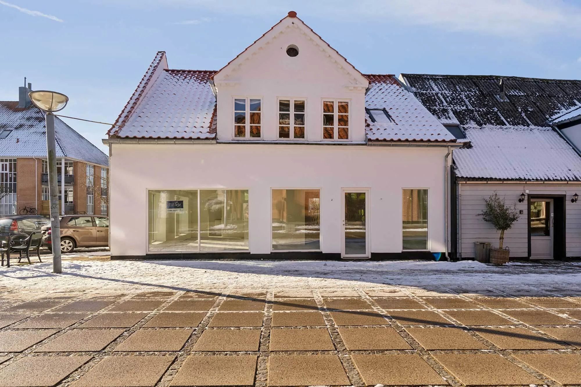 Butik med stort glasvindu og tegn på forretning. Snedækket tag og sne omkring. Moderne interiør og udvendigt design.