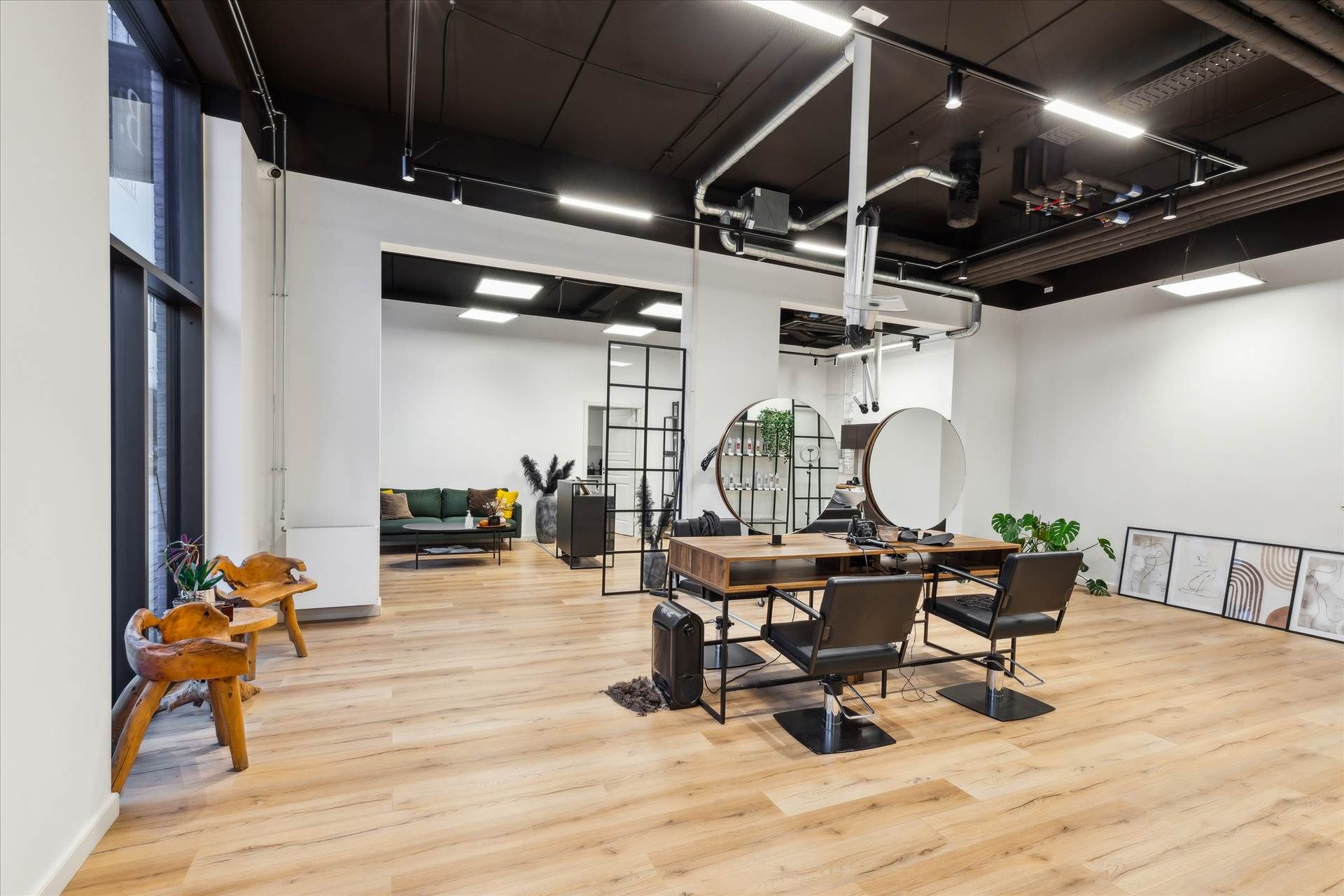 Inde i en moderne salon med hårfrisører og stol, hvor der er en sofa, plante og store spejle på væggen