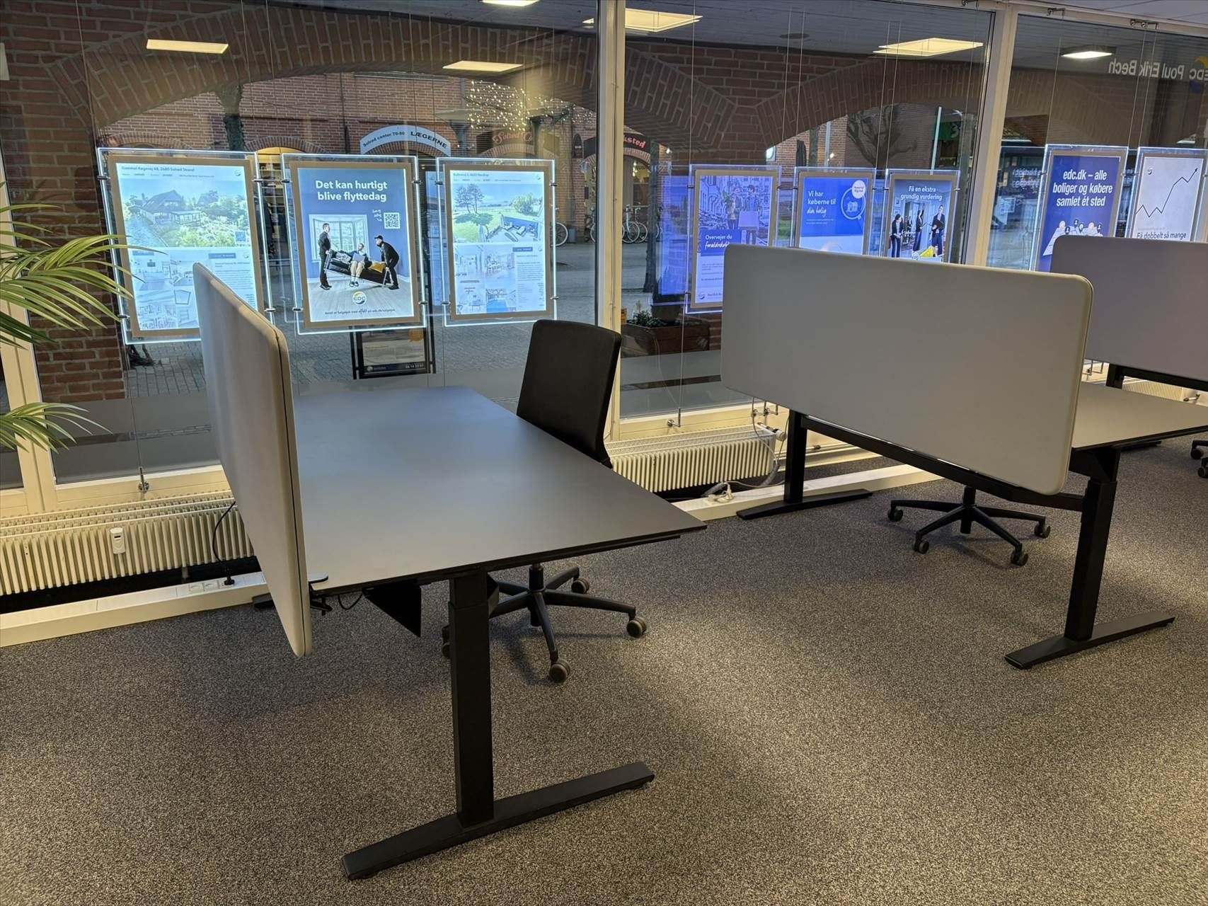 Kontorplads med skrivebord og høj glasdør til adgang til gårdhaven med planter og skulpturer