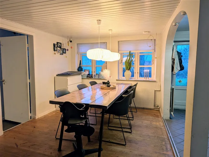 Langt borde i spisestuen med plante og lysekroner samt møbler og radiatorer