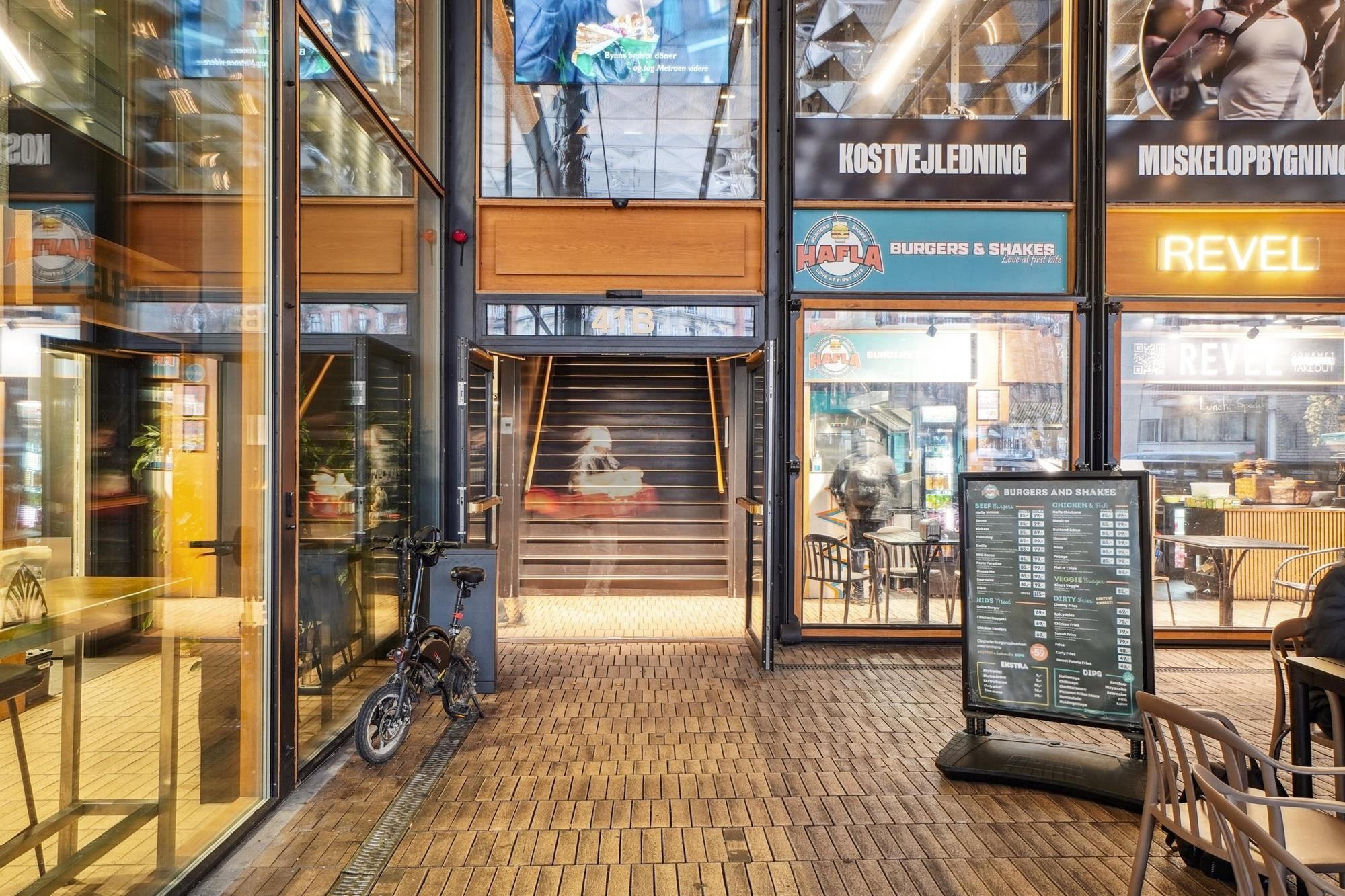 Foto af indgangsparti til et burgerrestaurant med skrifterne Burger & Shakes og Revel samt glasdøre og -vinduer