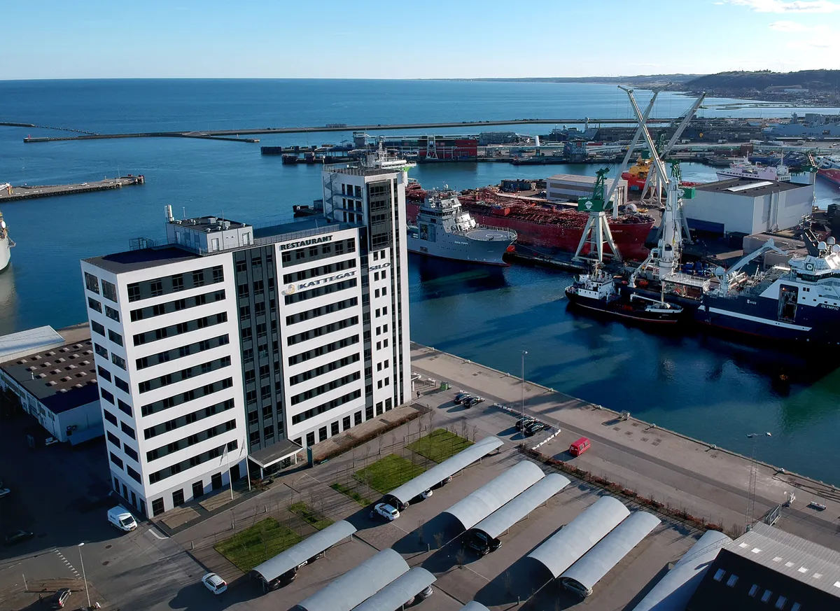 Kattegat Silo i Aarhus med lyse højhus med restaurant og søhavn med krydsende skibe og krane i baggrunden