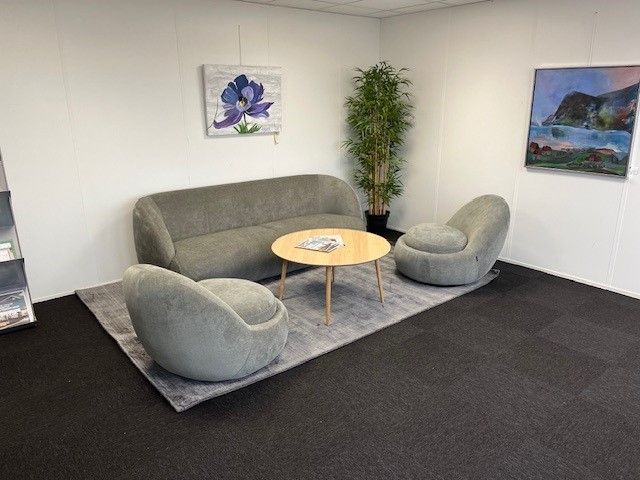 Herlevs BUCH BUSINESS CENTER med moderne møbler og kunstværker på væggen og et stort grønt træ i stuen.