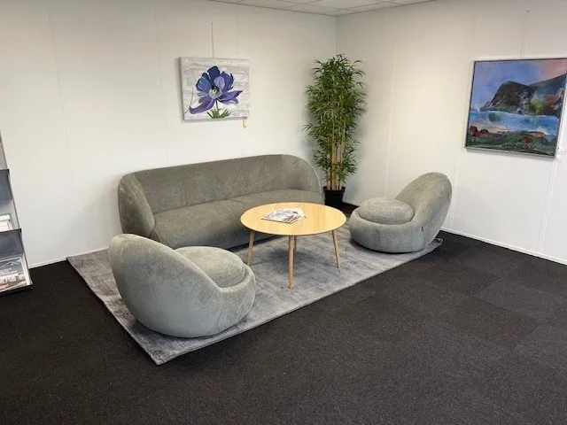 Herlevs BUCH BUSINESS CENTER med moderne møbler og kunstværker på væggen og et stort grønt træ i stuen.