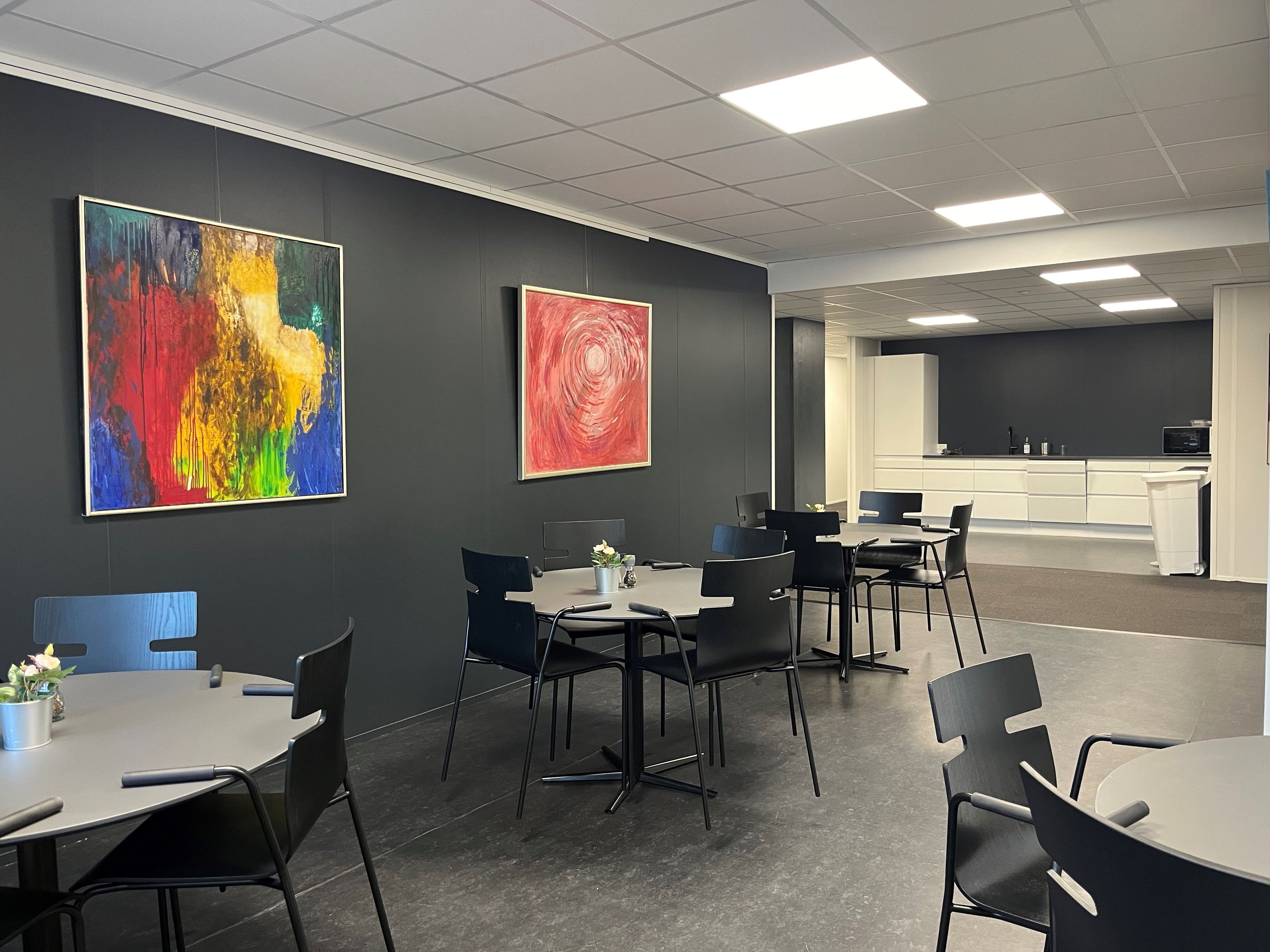 Moderne mødelokation med lyse loftslamper, moderne møbler og to malerier på væggen