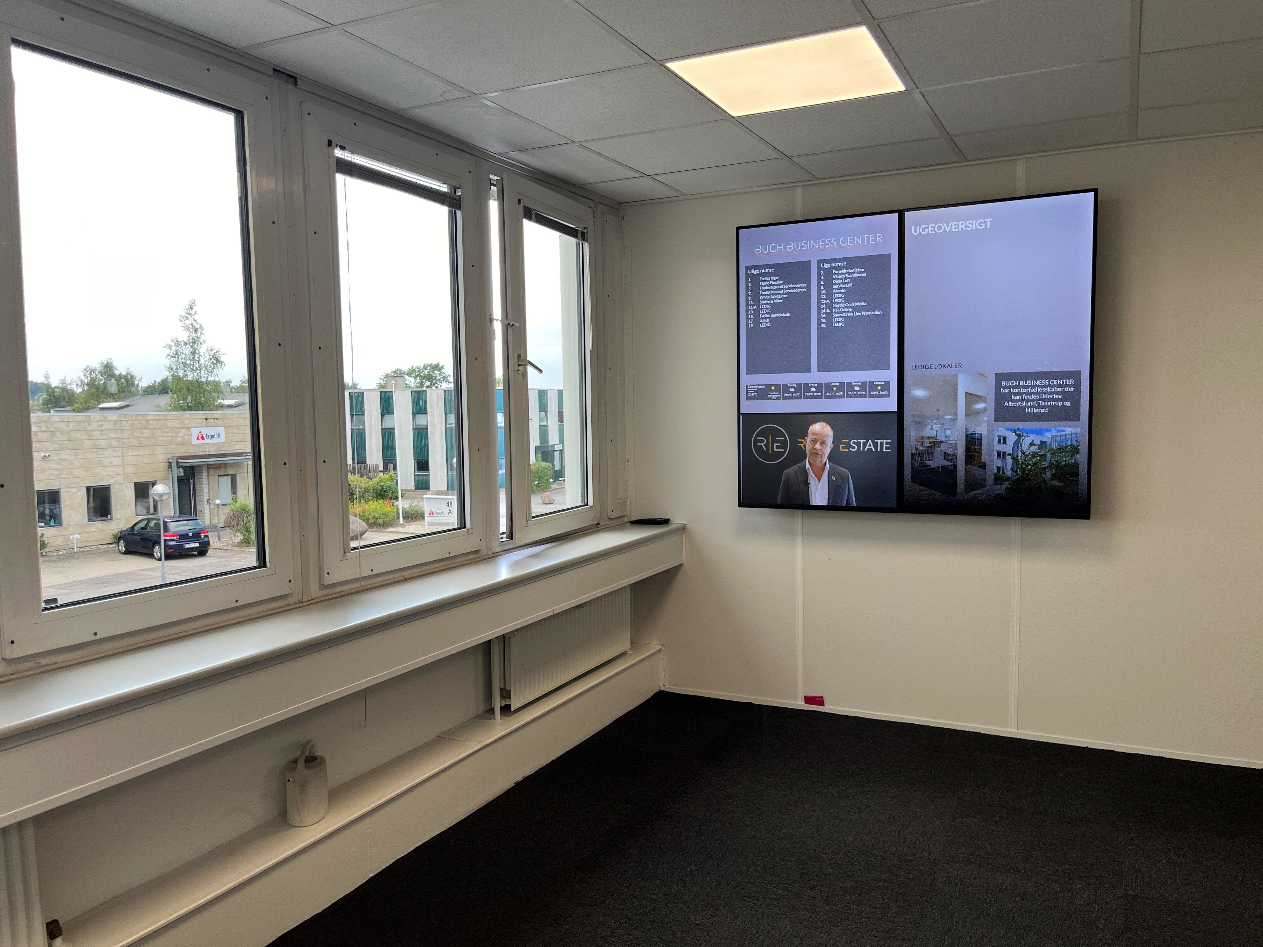 To store skærme viser skrift og billeder fra et business center med navnet Buch Business Center i Herlev. Der er en mand i