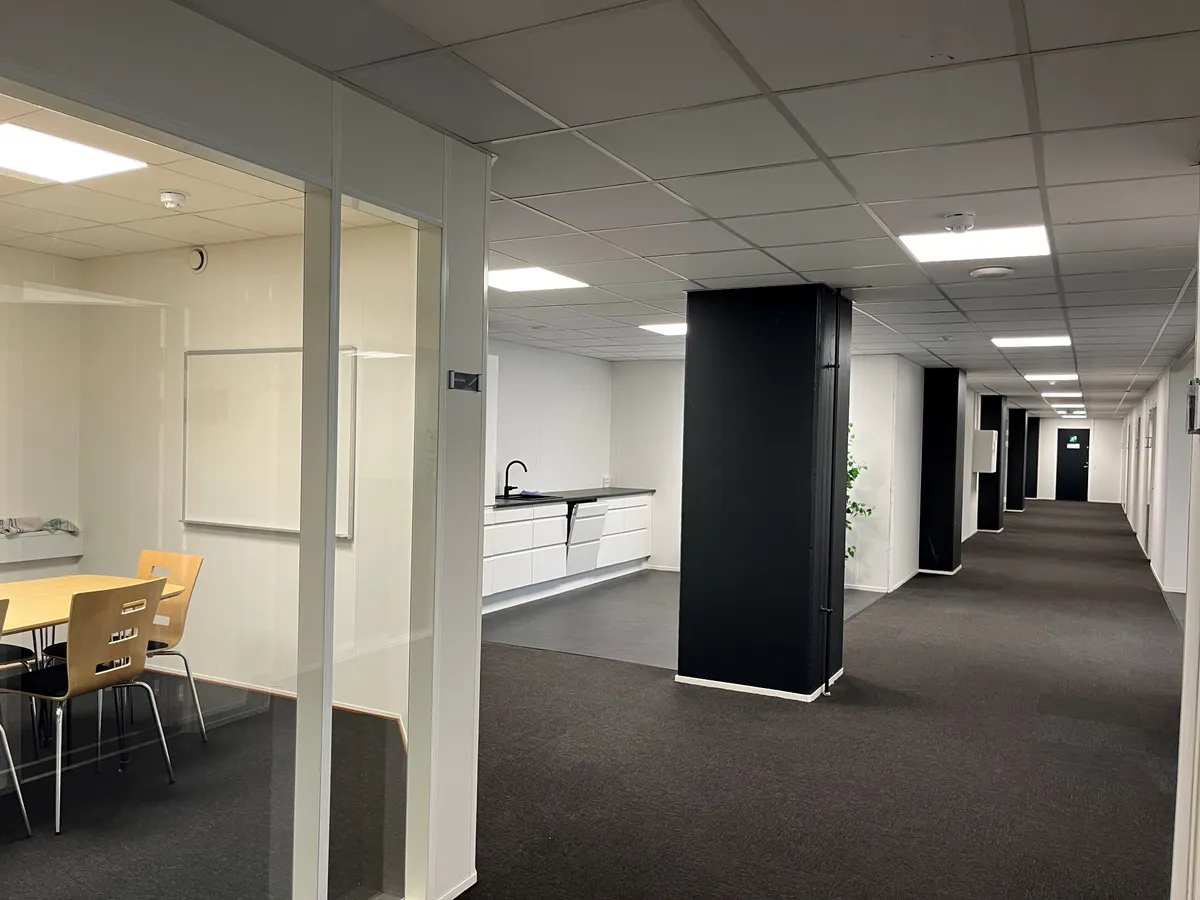 Billede af en moderne og ren kontorlokation med en åben stue og en bordsætning, der er klar til brug.