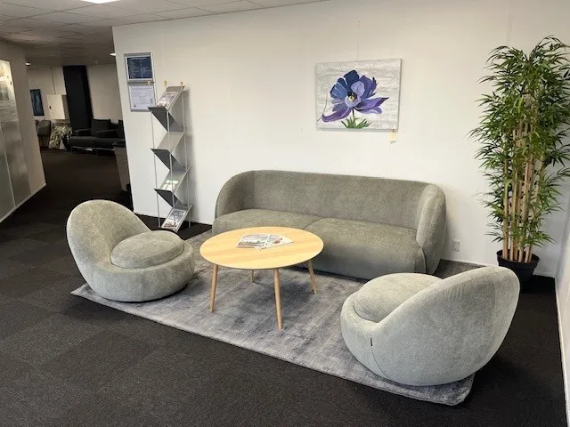 Fælles rum med tre runde stole, en sofa og et rundt bord med publikationer