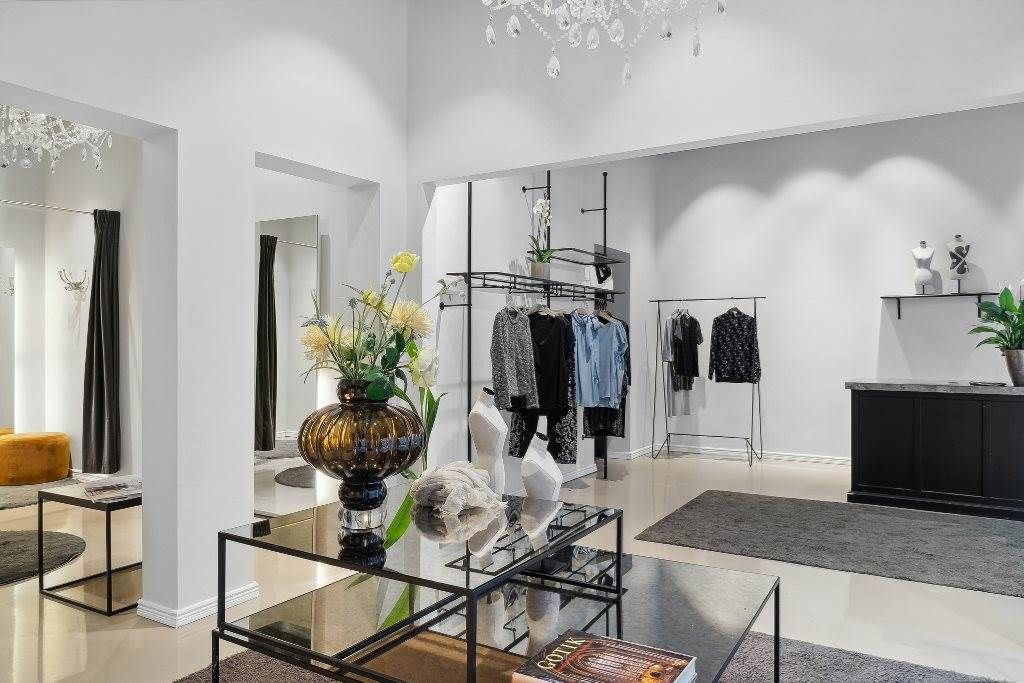 En moderne, luksuriøs butik med højt til loftet, lysegul væg og gulvtæppe, samt moderne møbler og dekorationer.