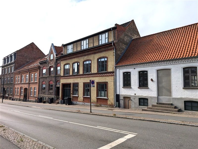 En tom og smal gade med røde mursten og hvide facader med gavle og vinduer i København