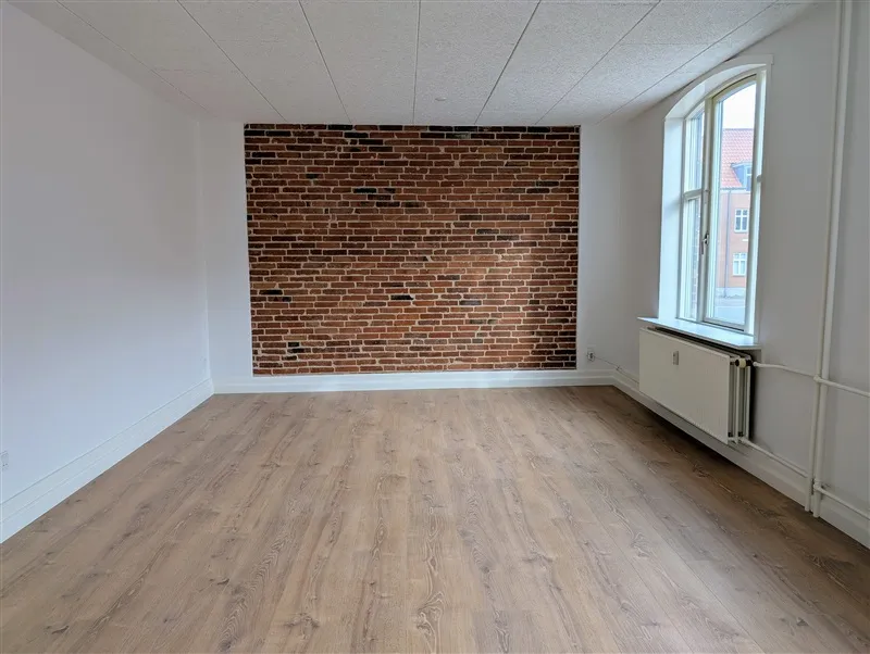 Store lyse stue med moderne gulvbelægning og lyse vægge, røde mursten og hvid gulv samt store vinduer