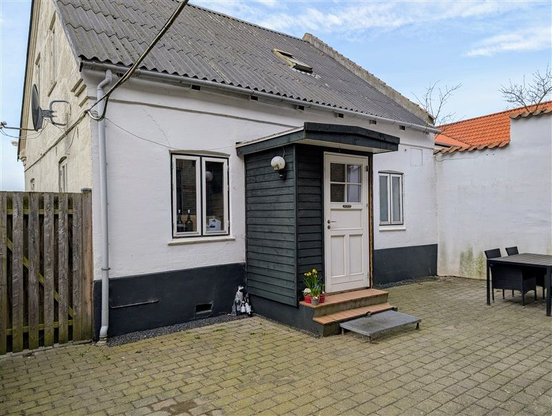 Den smukt renoverede villa med terrasse og have har en hvid og sort facade og en rød tagdækning