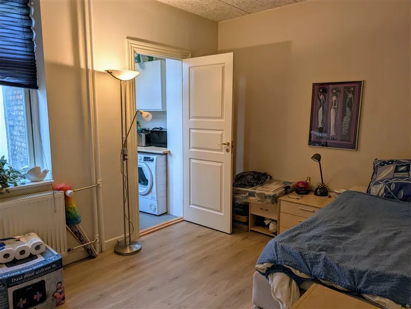 Renoveret soveværelse med trægulv og lyseforhold, hvor et sengelinned og to puder er udlagt på sengen