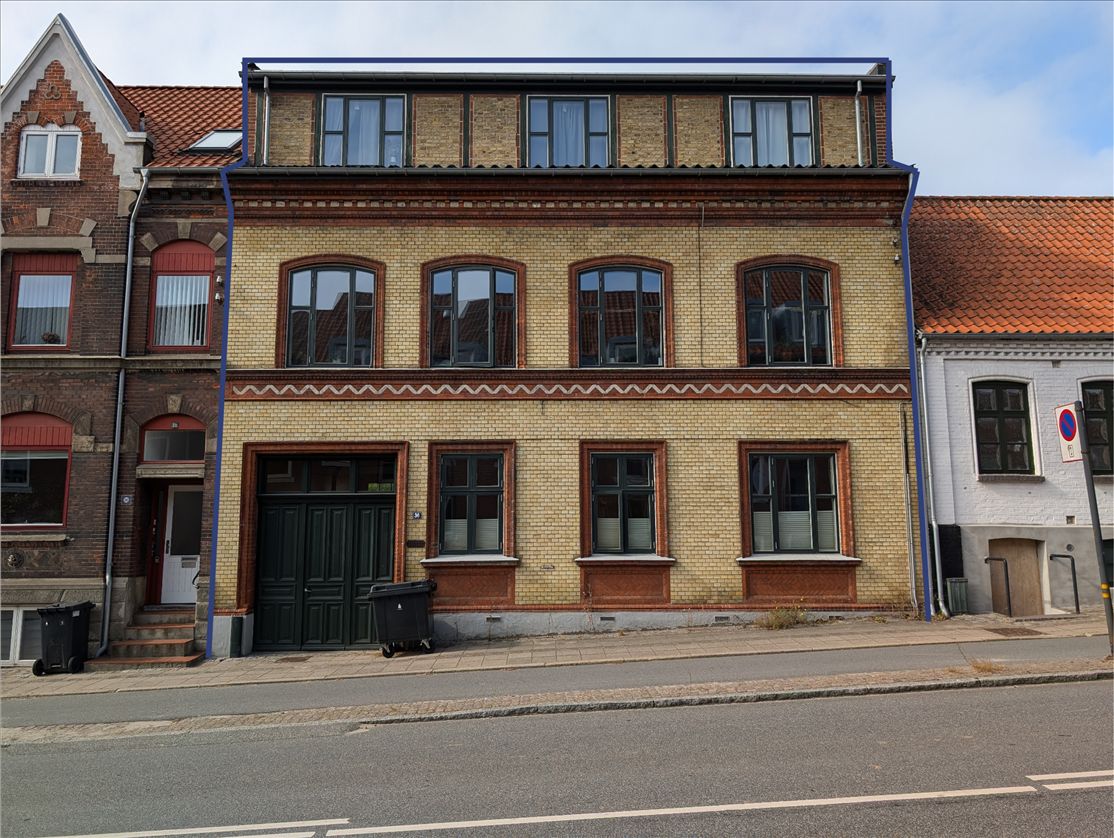 En tre-etagers ejendom med røde tegl og lyserøde vinduerne på Norgesgade 36