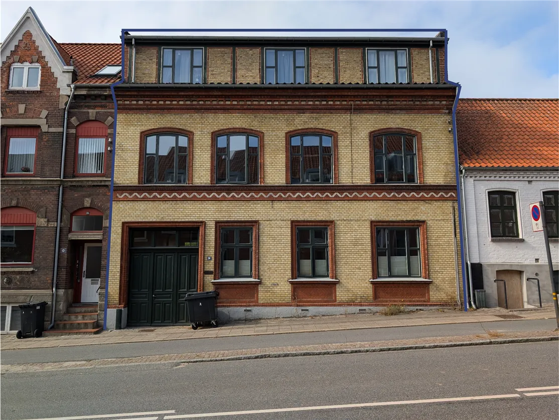 En tre-etagers ejendom med røde tegl og lyserøde vinduerne på Norgesgade 36