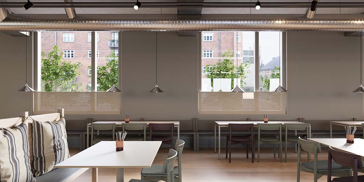 Et moderne café med bord og stole, hvor det er lyse og luftige og der er vinduer med grønne planter udenfor