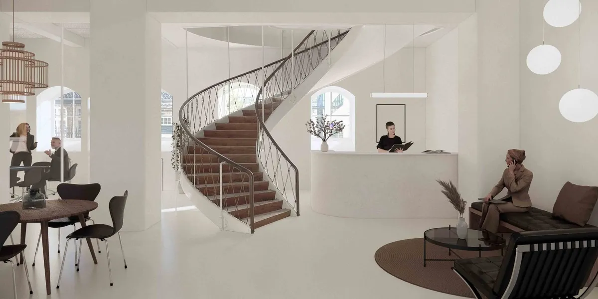 Et moderne kontor med hvide vægge og lyse lofter, et slankt trappeværk, og flere bordsæt og stole rundt omkring