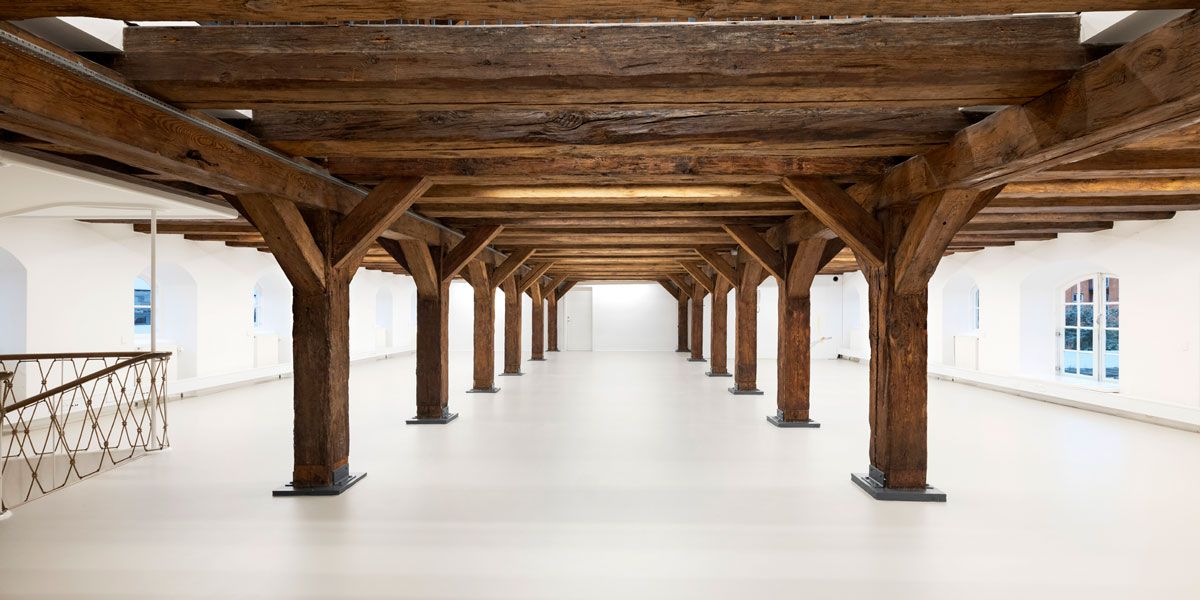 Det gamle pakhus indeholder en stor hal med træbjælker og hvide vægge og gulv samt et højt loft