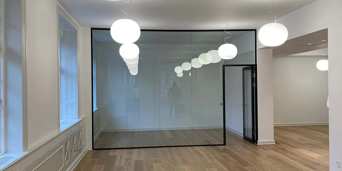 En hvid stue med lysekroner og gulvtæppe samt et stort glasparti og vinduesvisker