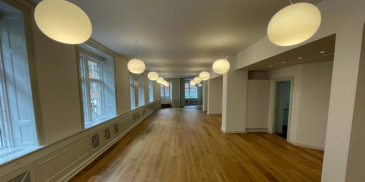 En lang og lyse hall med lysegule loftslampe, hvide vægge og store vinduer, der giver masser af naturligt lys til lyse,