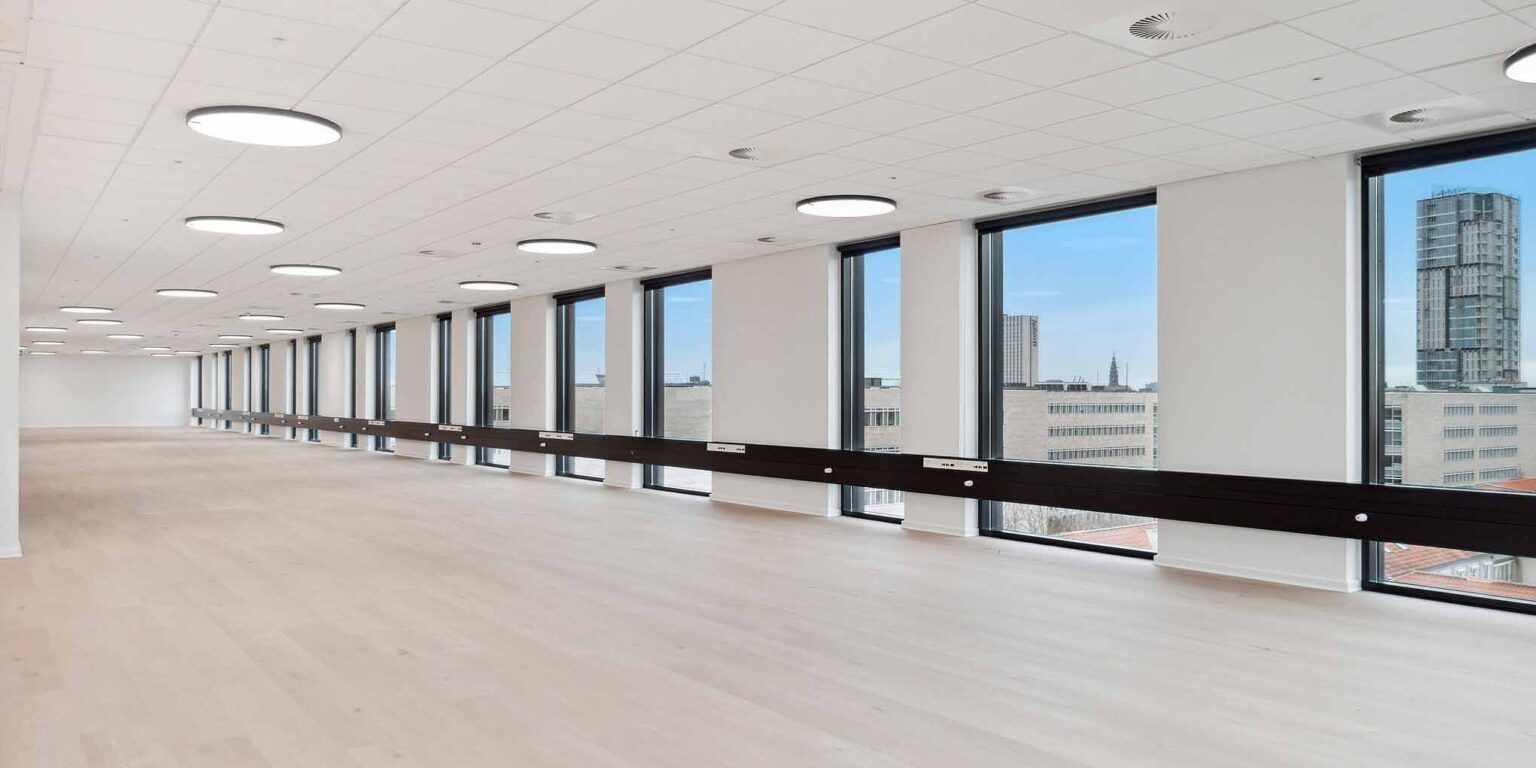 Store lyse lokaler med hvide vægge og gulv, højt til loftet, lyse runde loftslampe og flere store vinduer
