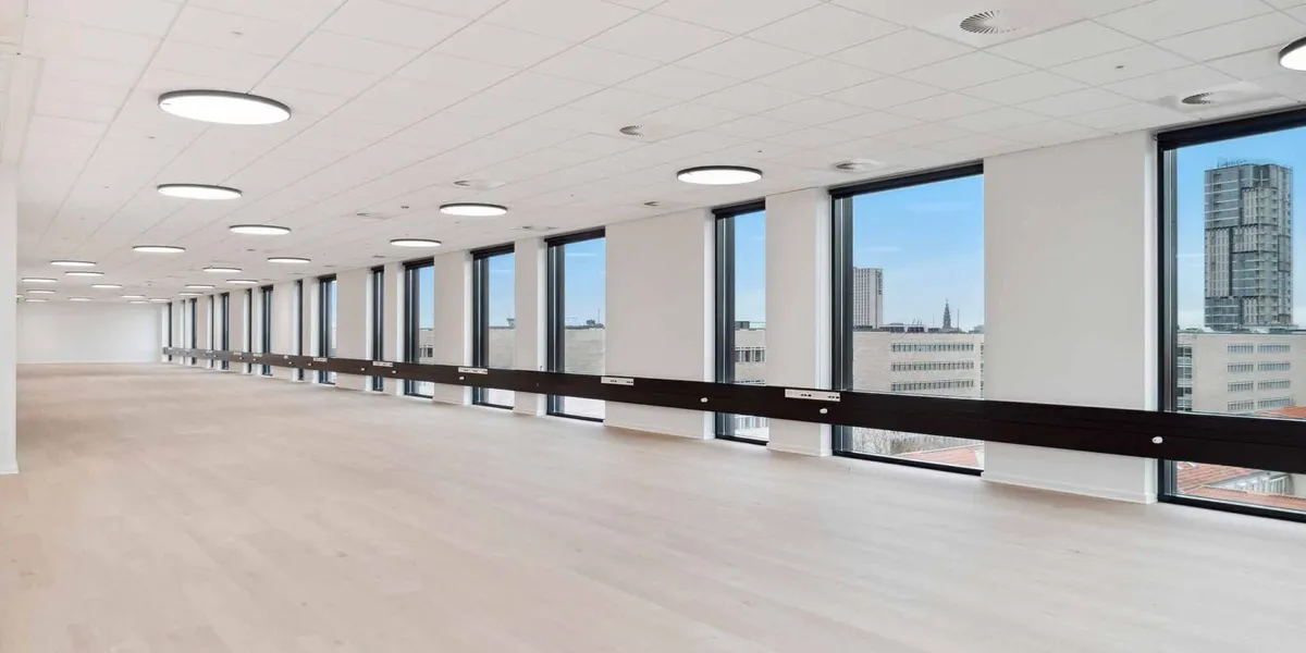 Store lyse lokaler med hvide vægge og gulv, højt til loftet, lyse runde loftslampe og flere store vinduer