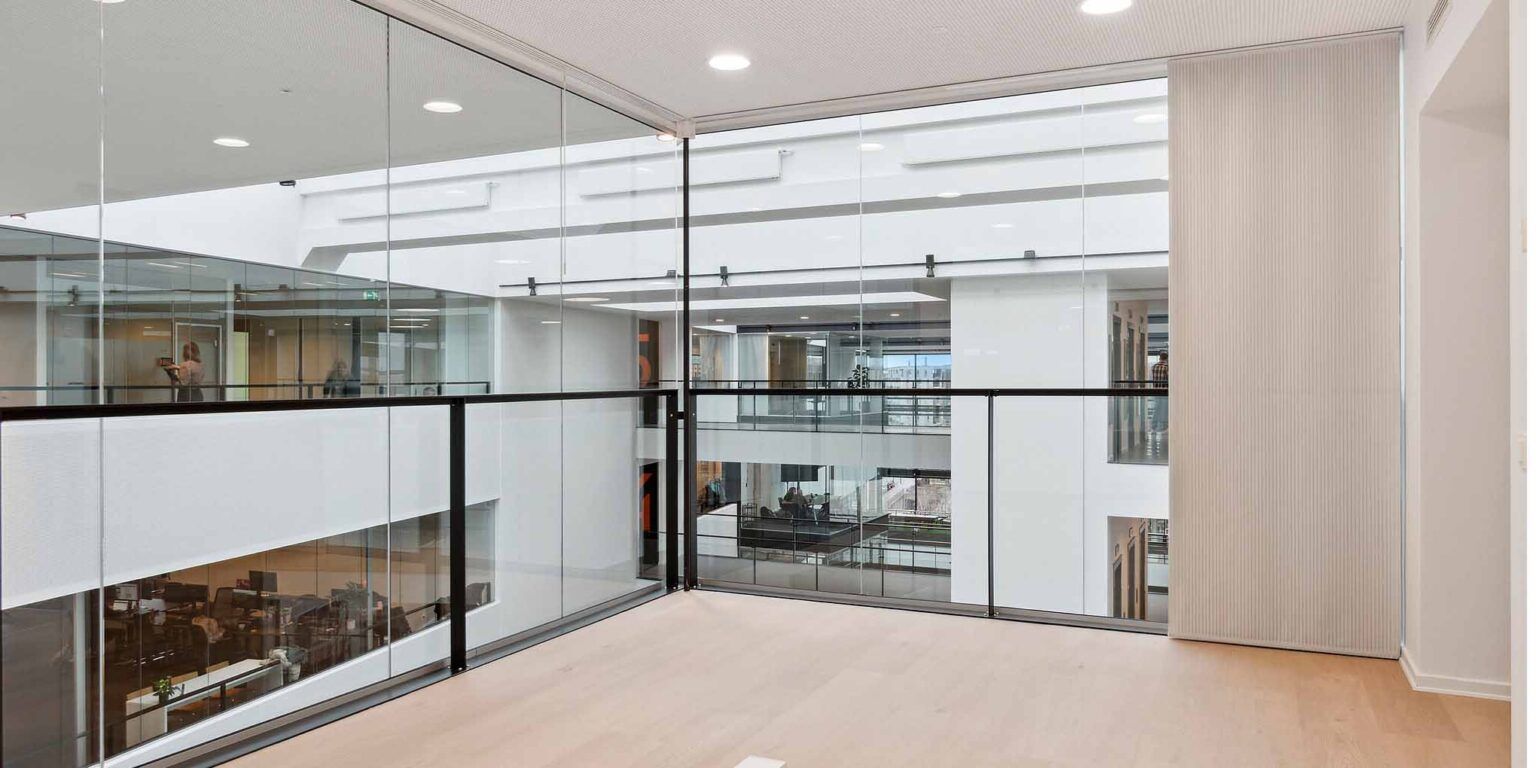 Inde i Mikado House med moderne, hvidt vægmaleri og glaspartier samt højloftede lokaler med lysekroner og loftsarme