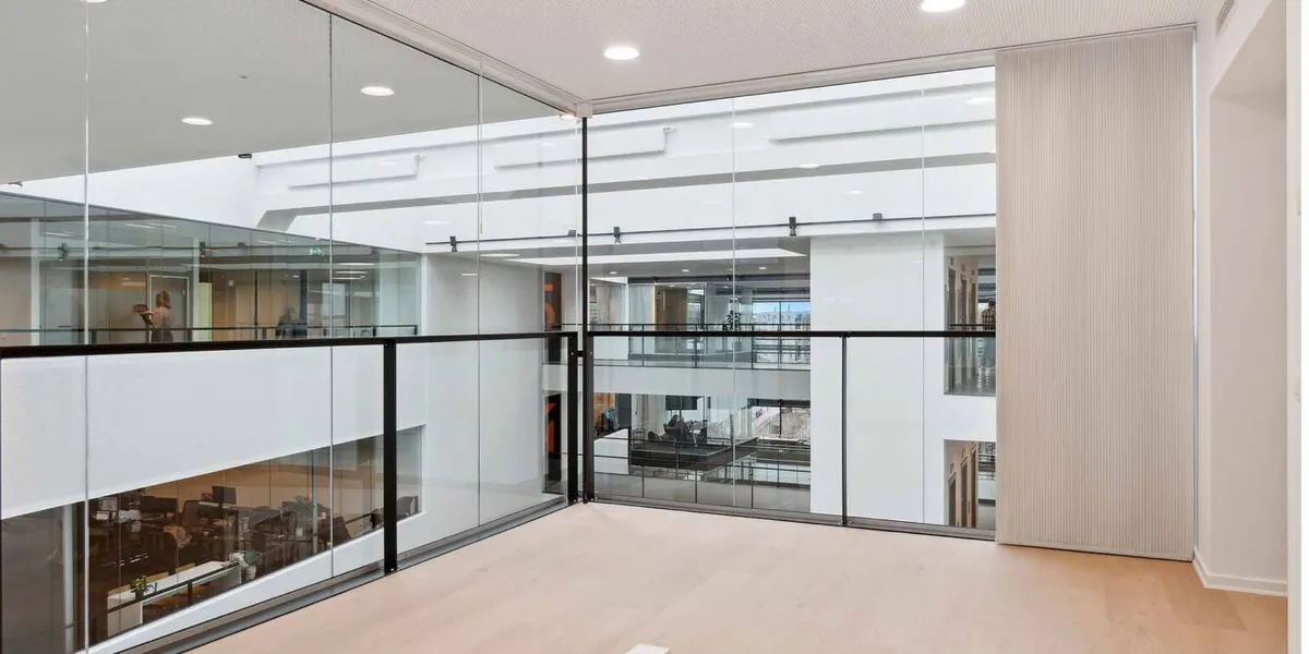 Inde i Mikado House med moderne, hvidt vægmaleri og glaspartier samt højloftede lokaler med lysekroner og loftsarme