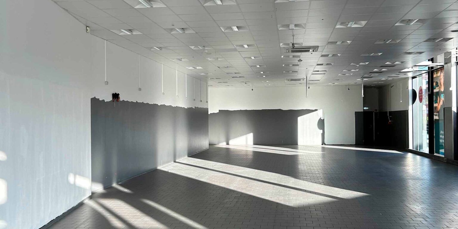 Ledigt butikslejemål med gulv og hvide vægge og nylige malerfarver i Mikado House, Islands Brygge.