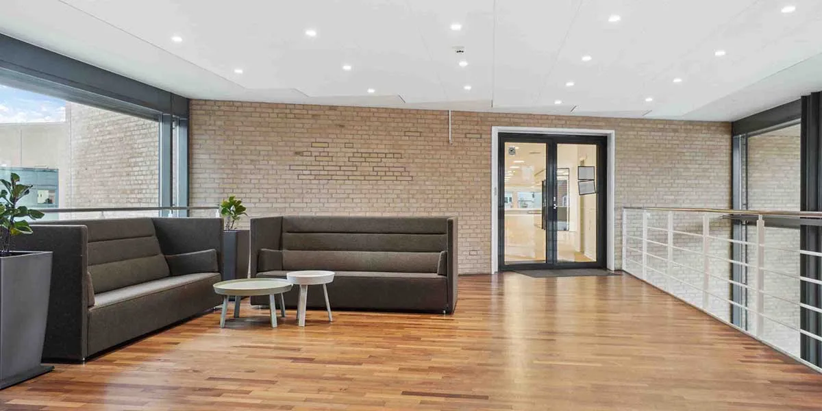 Værelse med moderne indretning, trægulv og lysegulvlampe, stol med sideborde og terrasse med metalrammer