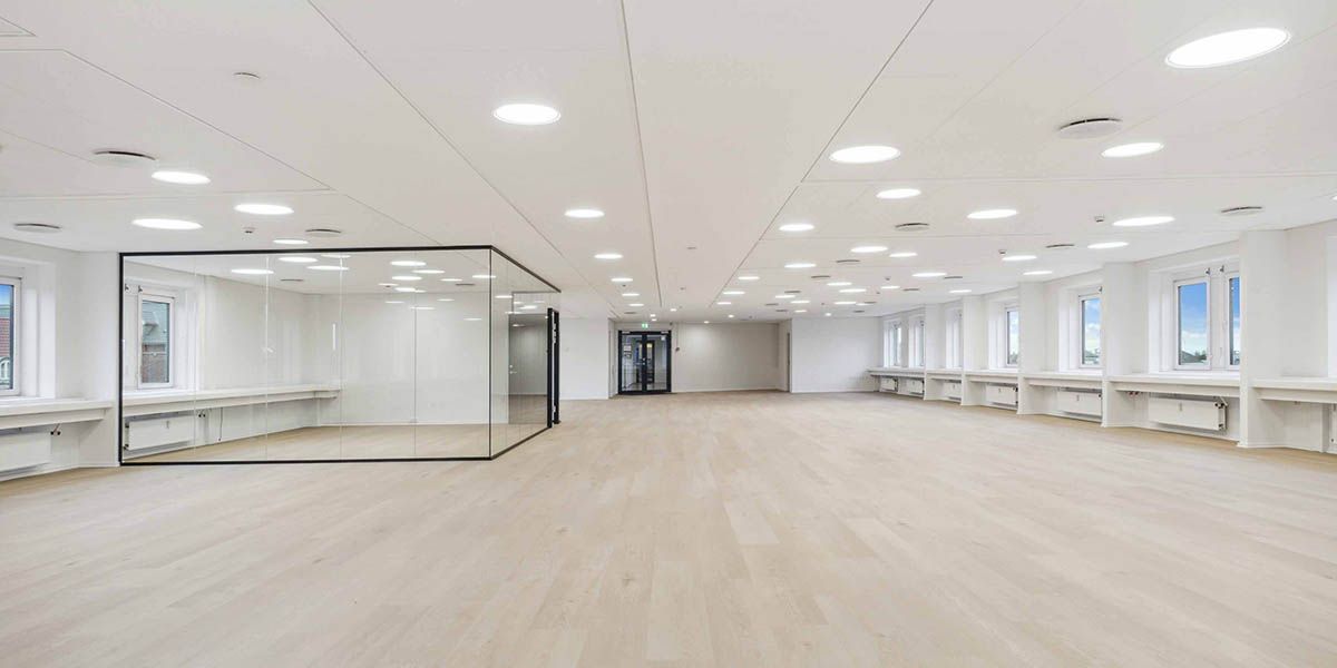 Tomt og pænt kontor med lyse gulve og store vinduer til meget lys og gode arbejdsforhold