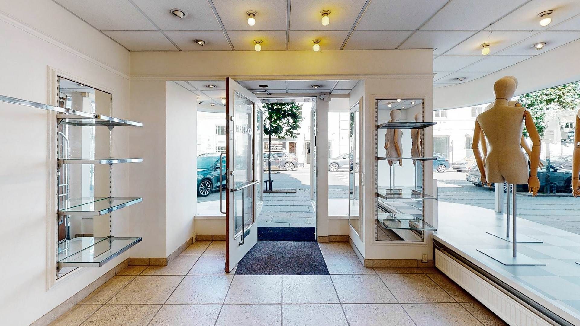 Indenfor en smuk ejendom ses flere store spejle og en åben dør til en stor butiksforretning