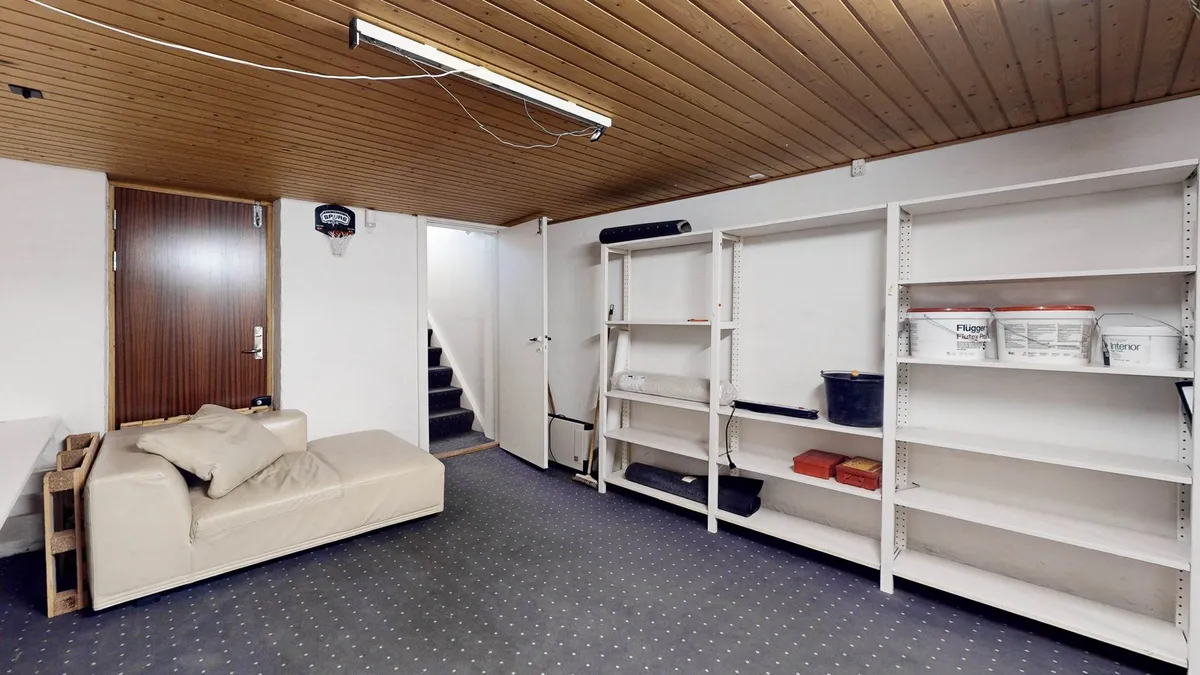 En stor hvid skab med flere hylder, et hjørneskab med en pude og en sofa samt en basketballring