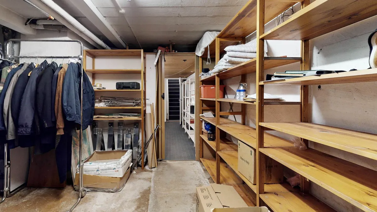 Tidligere lager med tøj, bøger, papkasser og diverse genstande i en lyse, rummelig rum.