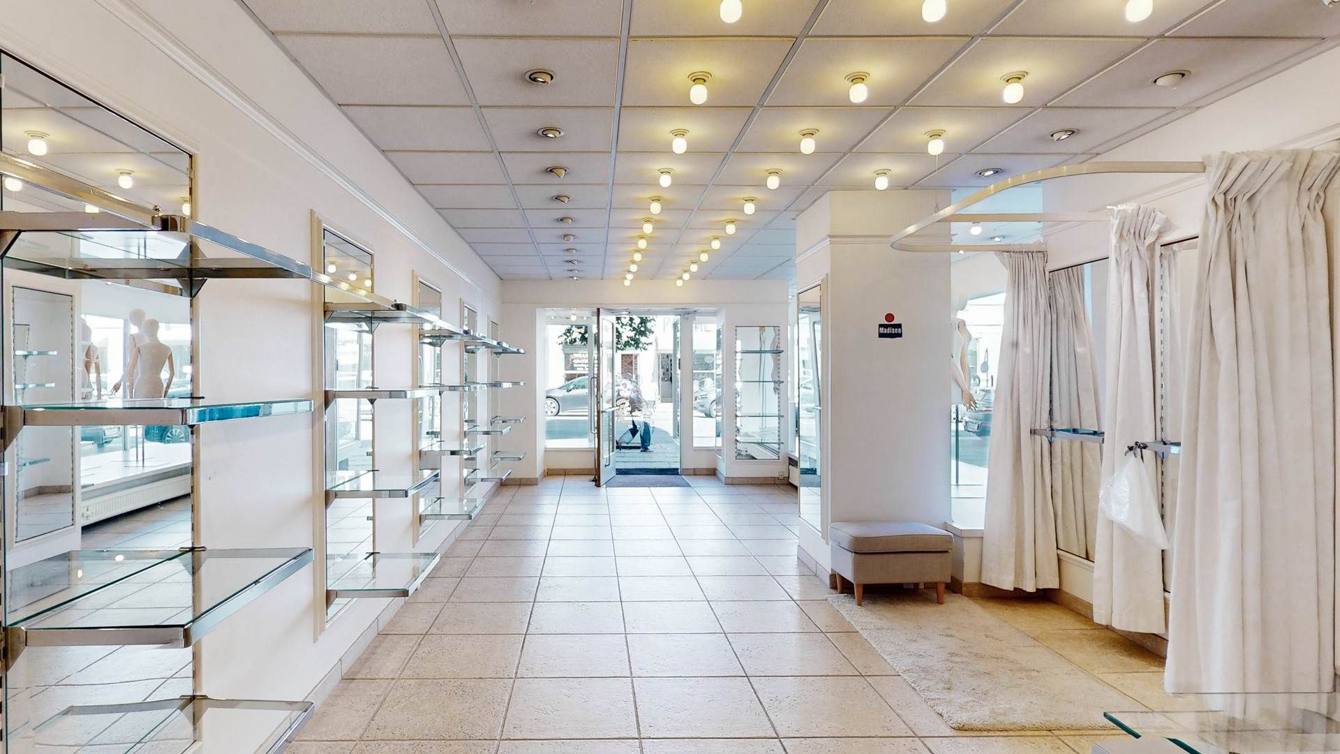 Indenfor erhvervslokaler med høj loftshøjde og moderne indretning, hvor der er lysekroner og gulvbelægning i marmor.