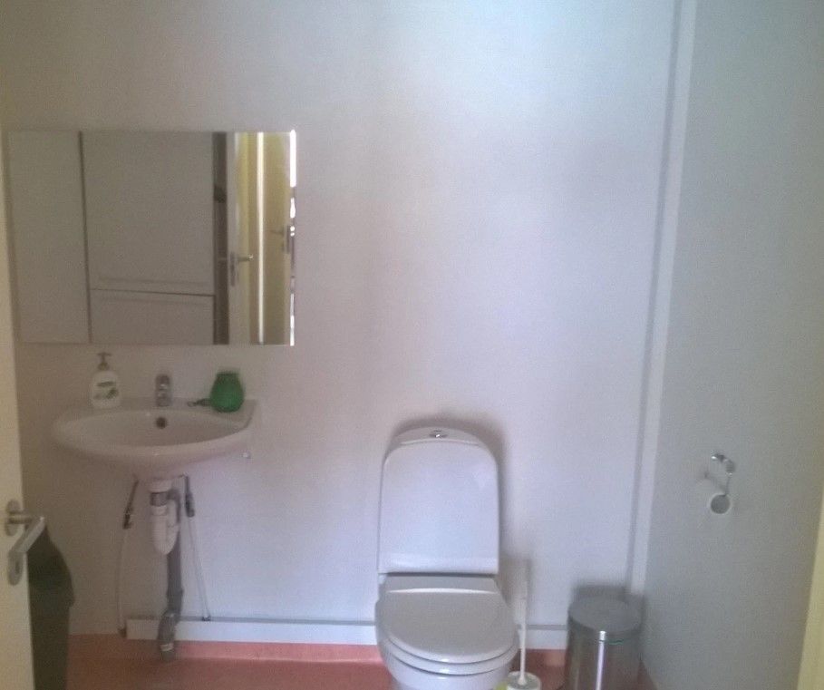 En hvid badeværelse med en hvid toilet, en hvid vask og et spejl og en hvid kabinet på væggen