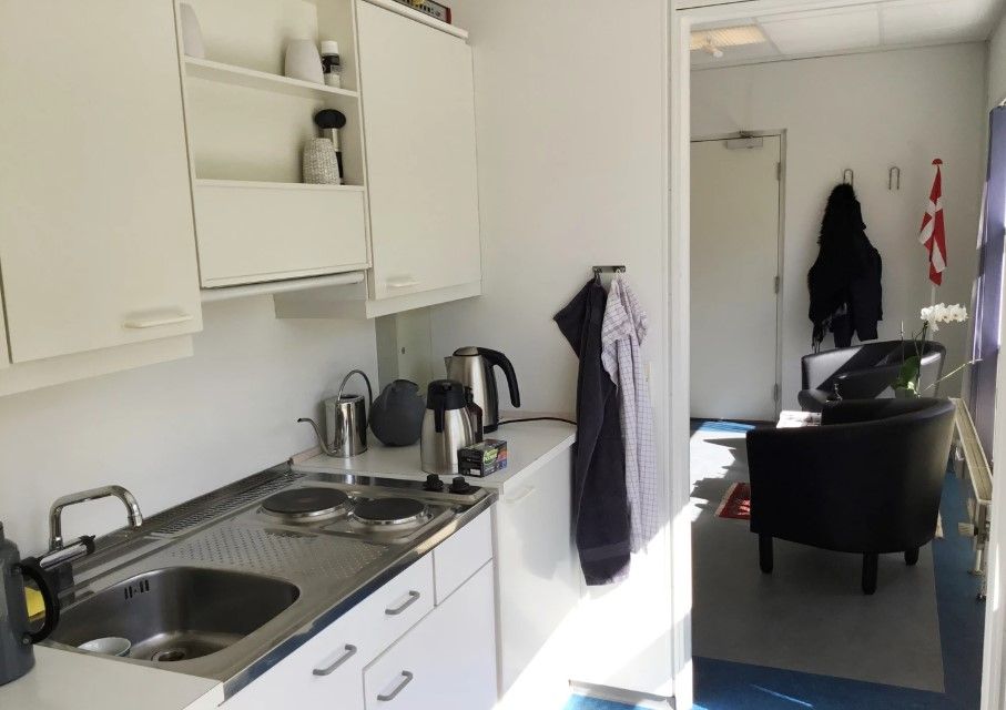 Lyst kontor med hvide vægge og møbler samt lyseblå gulvbelægning