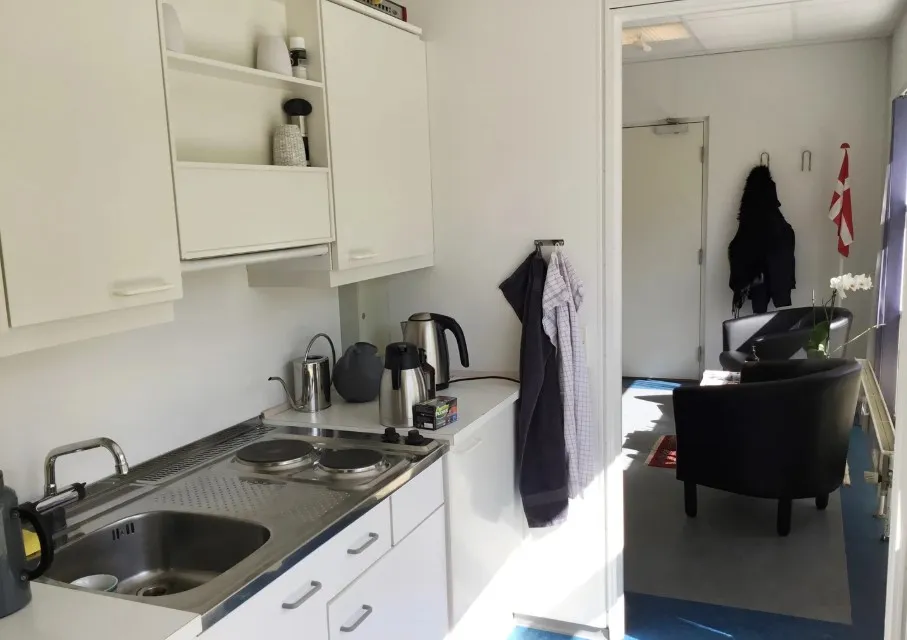 Lyst kontor med hvide vægge og møbler samt lyseblå gulvbelægning