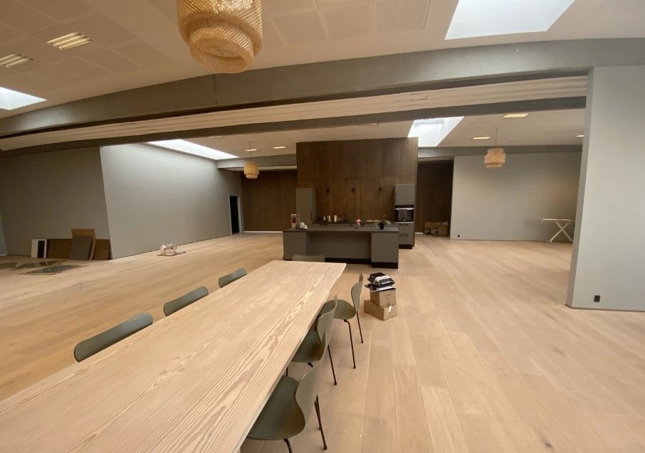Rummeligt kontorlokale med moderne møbler og lyse lofter, der er i gang med renovering og indretning.
