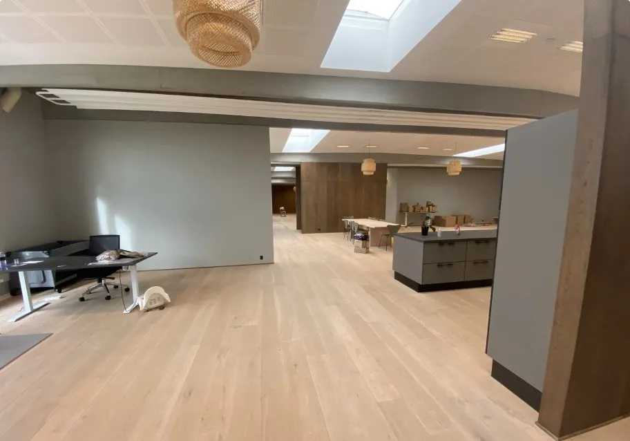 Kontorlokale med møbler og højt loft samt lysegul trægulv og moderne interiørdesign