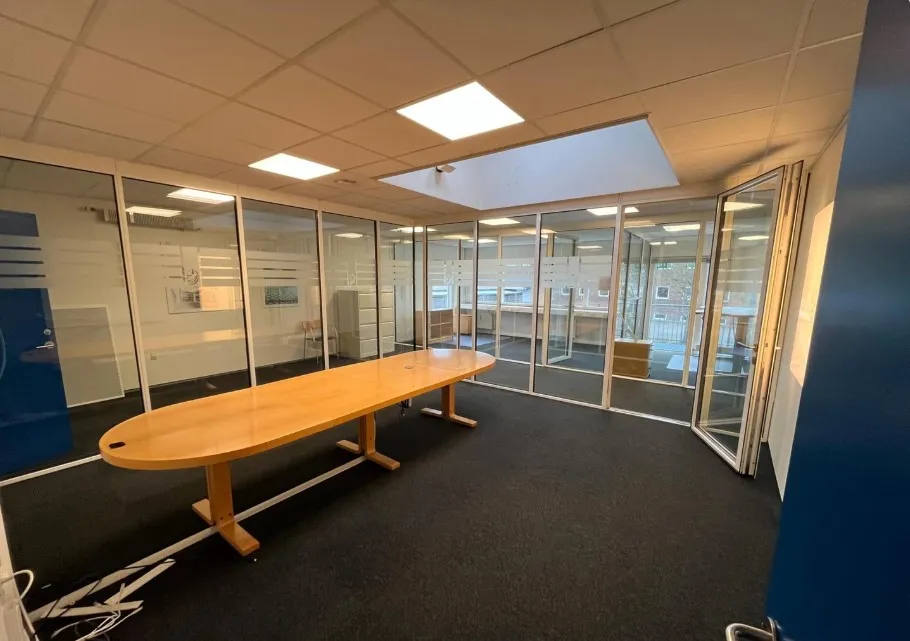 Lyst og rummeligt kontor med lange borde og glasvinduer i Viby J
