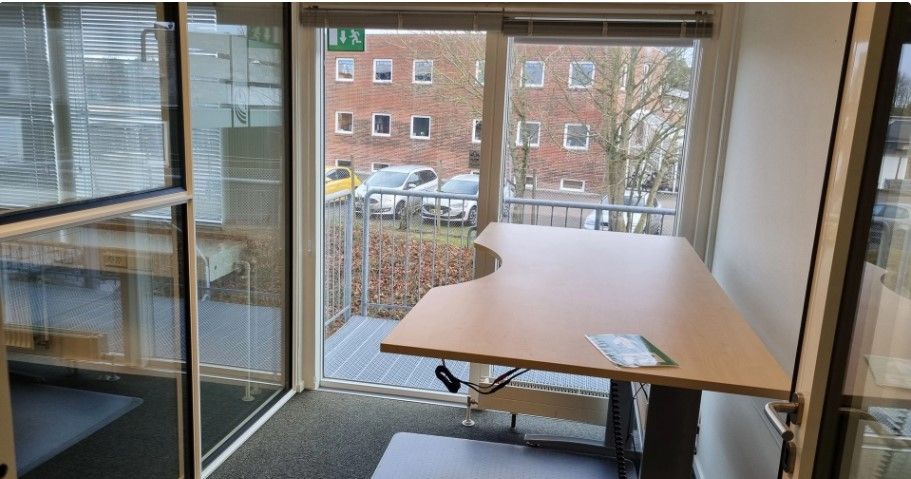 Et moderne kontorlokale med glasdøre og -ruder samt en stor skrivebord, der er placeret på en terrasse med udsigt til