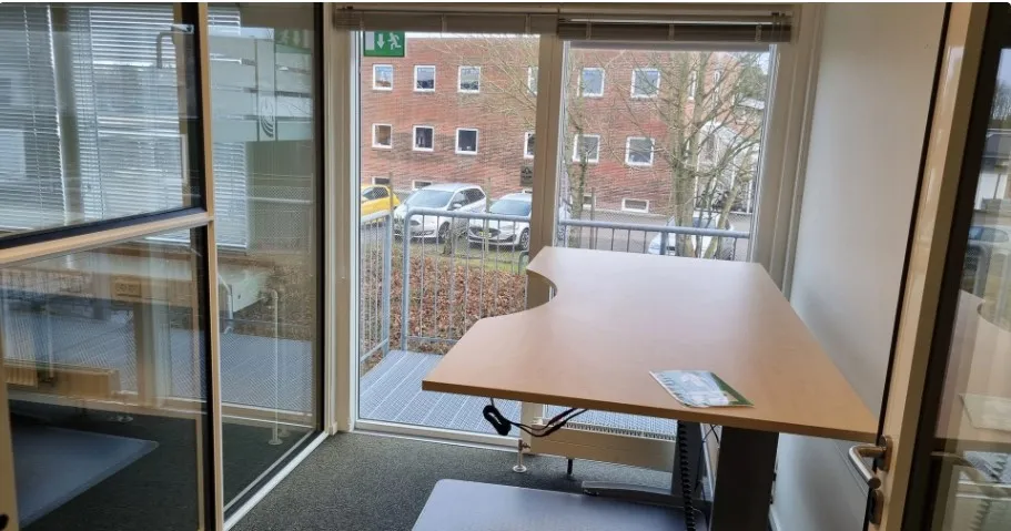 Et moderne kontorlokale med glasdøre og -ruder samt en stor skrivebord, der er placeret på en terrasse med udsigt til