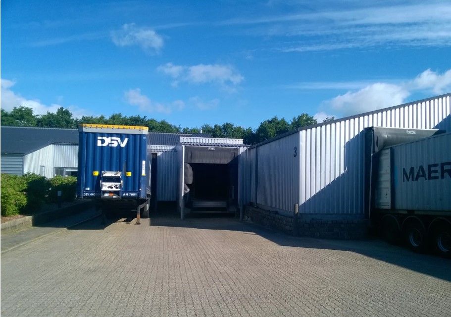 DSV-lastbil parkeret foran lejemål på Kinch Alle 1 i Løsning, med en stor lagerbygning og grønne planter bagved