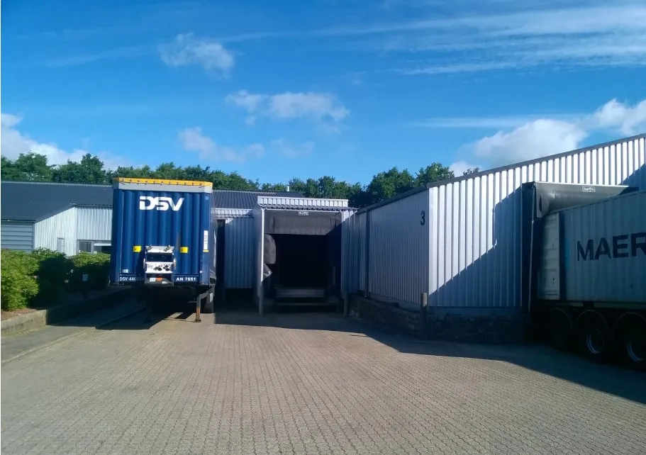 DSV-lastbil parkeret foran lejemål på Kinch Alle 1 i Løsning, med en stor lagerbygning og grønne planter bagved
