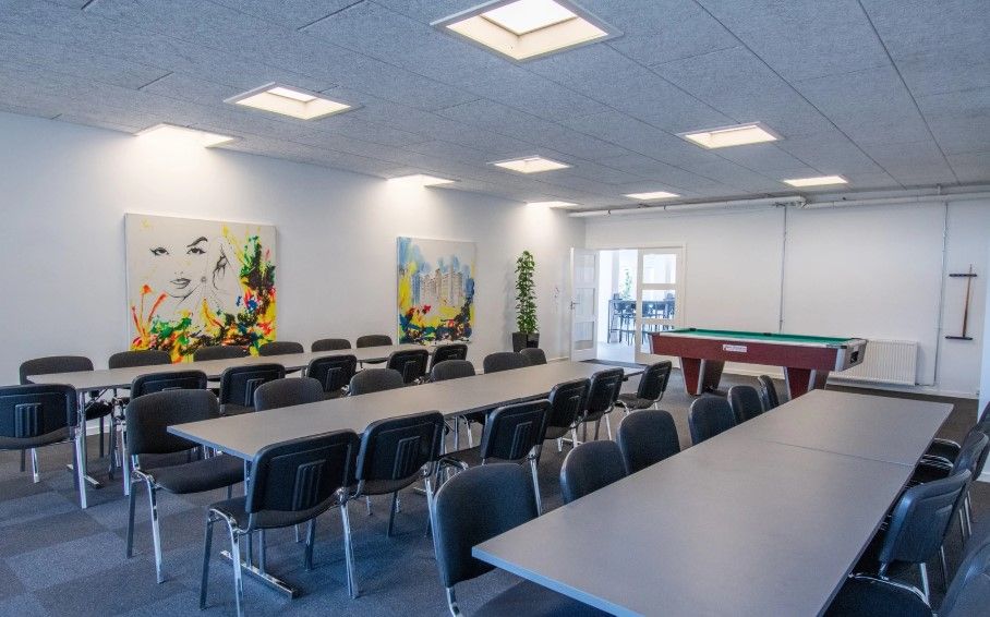 Kontorlokaler med mødesal og poolbord, moderne indretning med billeder på væggen og trægulve.