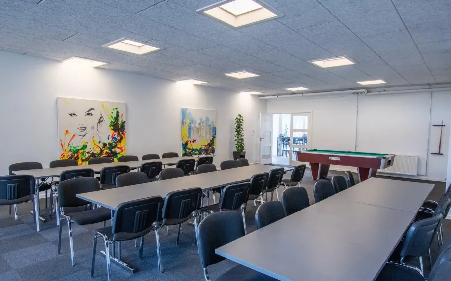 Kontorlokaler med mødesal og poolbord, moderne indretning med billeder på væggen og trægulve.