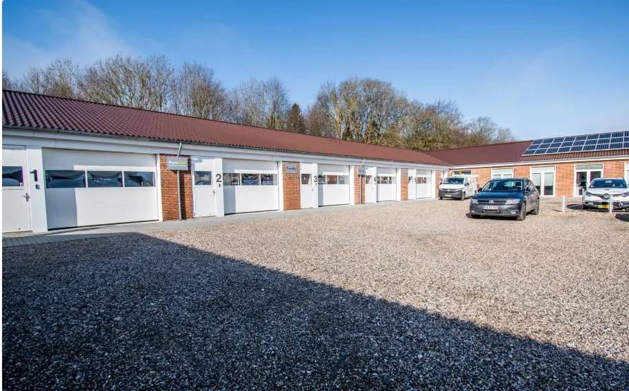 Lej kontor i kontorfællesskab med mange muligheder, flere biler parkeret og et hus med solceller på taget