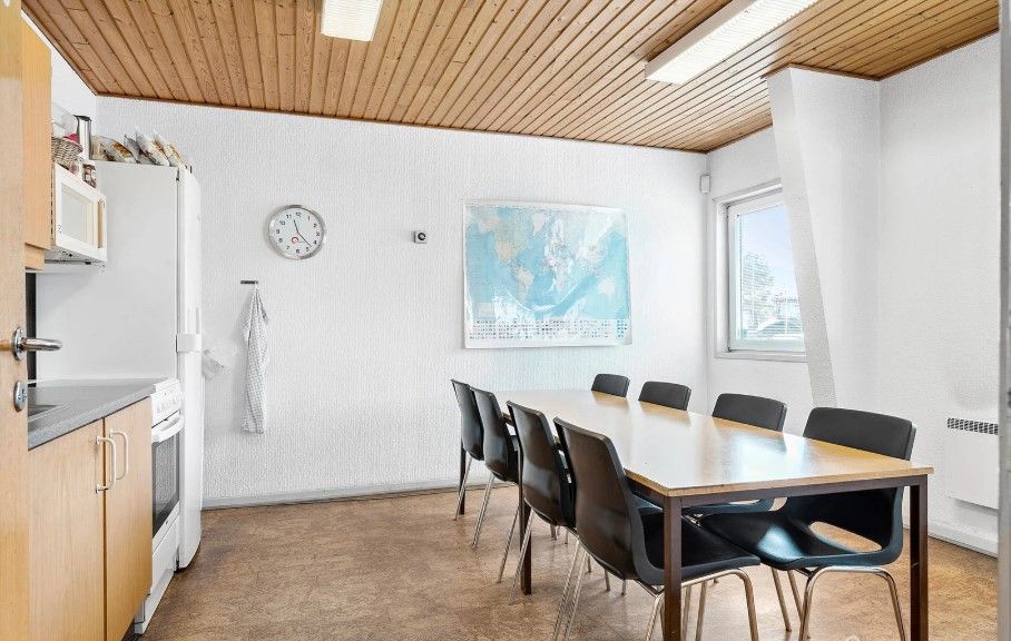 En industrikøkken med en stor spiseplads med borde og stole og en køleskab og mikroovn på siden