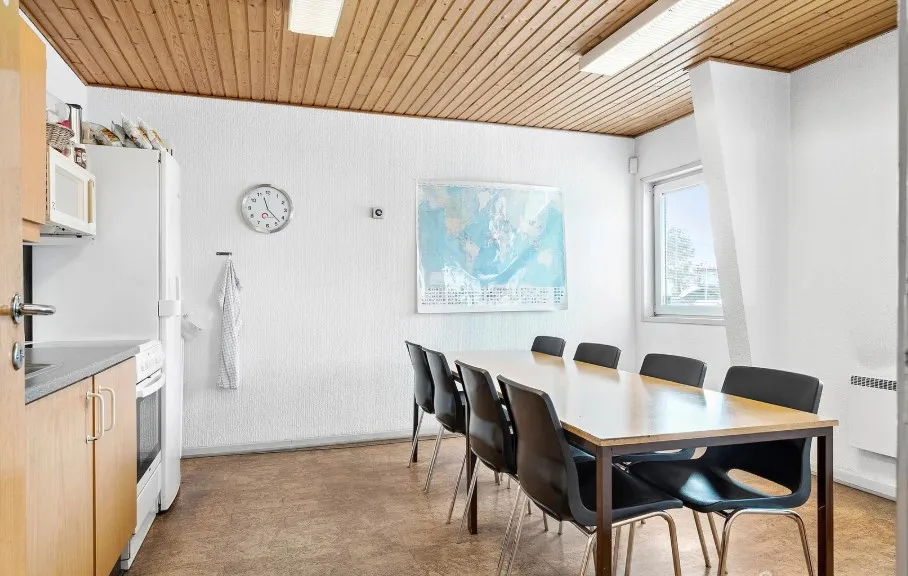 En industrikøkken med en stor spiseplads med borde og stole og en køleskab og mikroovn på siden